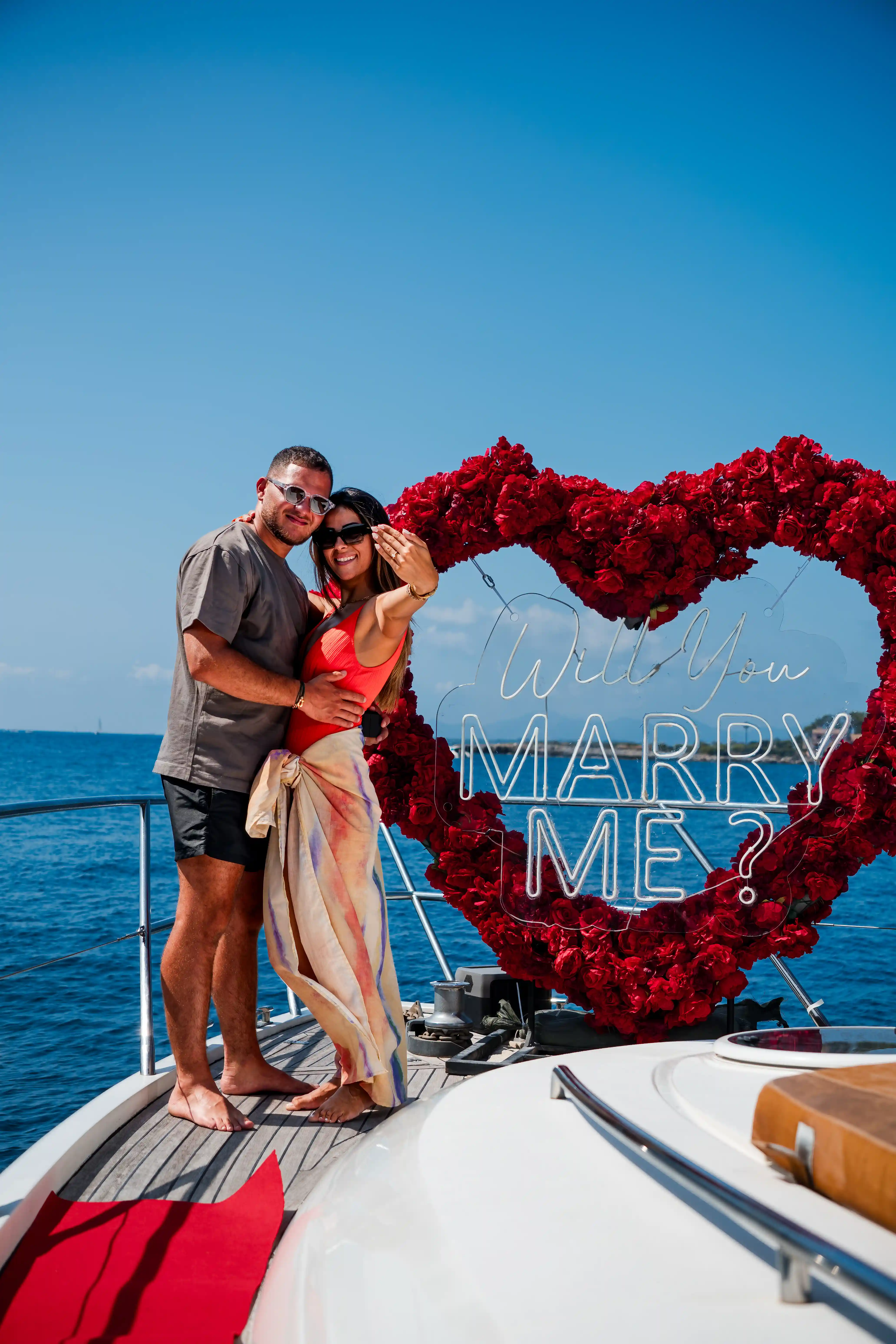 Demande en mariage sur le pont d'un yacht, devant un cœur de roses rouges